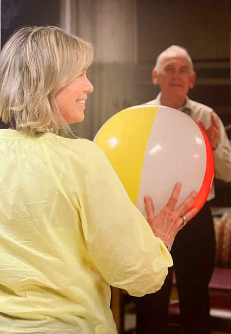 Therapist throws beach ball with Resident