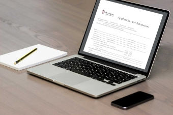 smartphone and notepad beside laptop with admission application